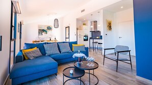 Ein modernes Wohnzimmer mit einem blauen Sofa, einem Couchtisch und einem Essbereich mit Stühlen.