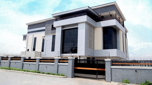 A modern two-story house with a balcony, large windows, and a gated entrance. - Skyline View Hotel and Suites (Abuja)