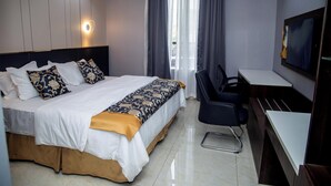 A hotel room with a bed, a desk, a chair, a TV, and an air conditioning unit. - Skyline View Hotel and Suites (Abuja)