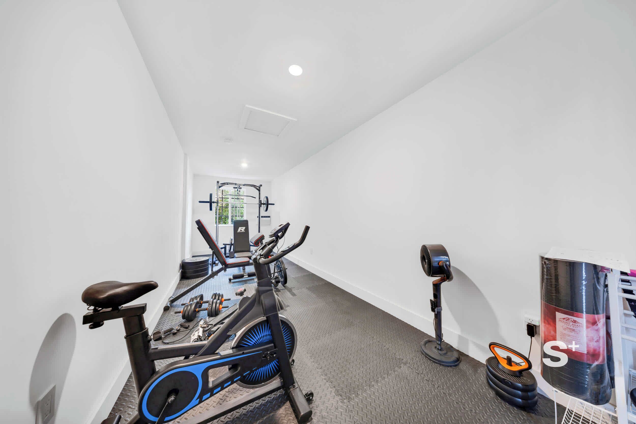 A gym with exercise bikes, a treadmill, and weight equipment.