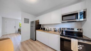 Una cocina moderna con armarios blancos, un refrigerador de acero inoxidable, un microondas, una estufa y un lavavajillas.