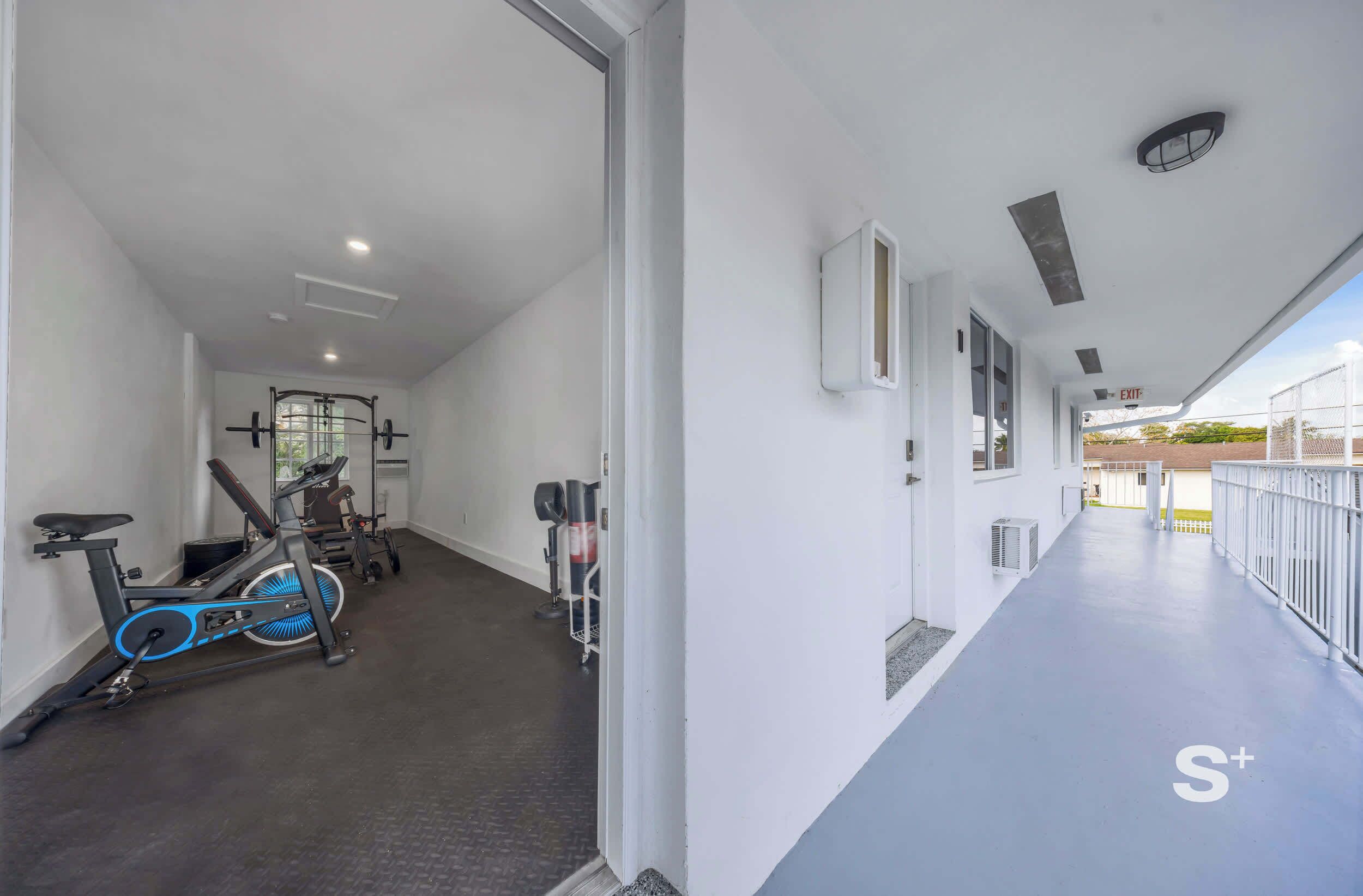 Une salle de sport équipée de matériel d’exercice et un couloir doté d’une rambarde.