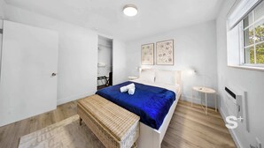 A bedroom with a bed, a bench, a bedside table, and a window. - Stylish 1-BD Apt  | Gym, BBQ, Free Parking (Miami)