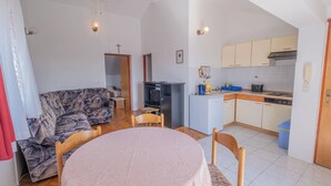 Ein kompakter Wohnbereich mit Essbereich, Sofa, Küchenzeile und Deckenventilator.