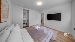 Ett modernt sovrum med en säng, en platt-TV och en rymlig klädkammare.