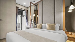 A modern hotel room with a large bed, a bedside table, a mirror, and a view of the outside. - Hinata by Kozystay - Sudirman (Jakarta)