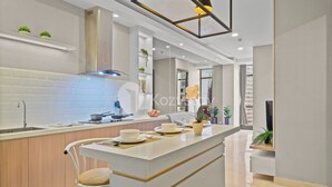 A modern kitchen with a central island, white cabinetry, and a built-in stove. - Hinata by Kozystay - Sudirman (Jakarta)