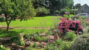 A garden with various plants and flowers, a stone structure, and a lawn. - Romantic Chalet- Hot Tub- Games Room-stream-views (Longhope)