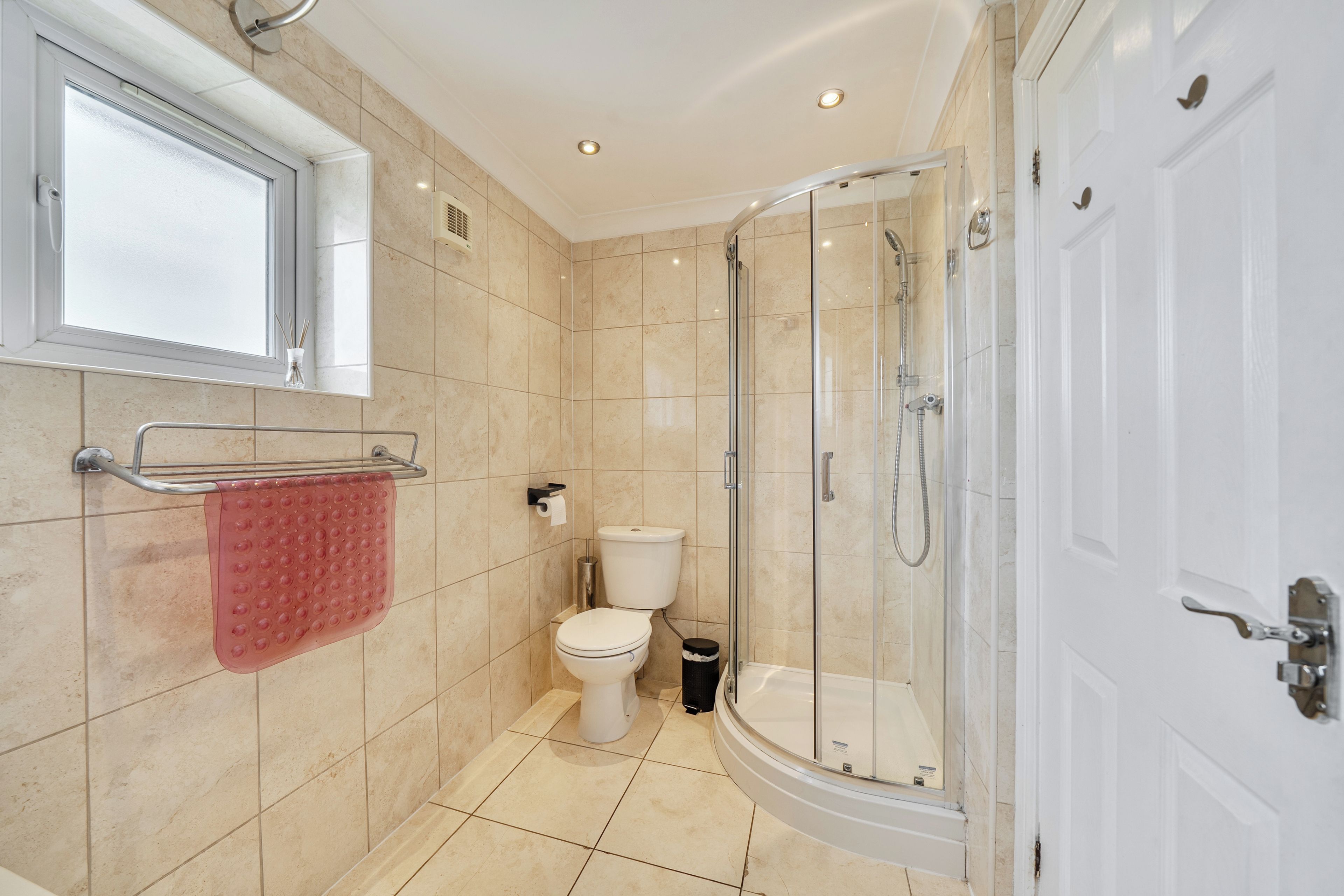 A modern bathroom with a glass-enclosed shower, a toilet, and a sink.