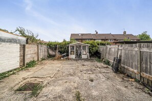 A backyard with a small shed, a concrete path, and a wooden fence. - 3-bed - Sleeps 5 - Pets - Parking (Northolt)