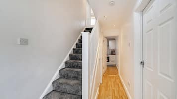 A staircase leading to a kitchen with white cabinets and a wooden floor.
