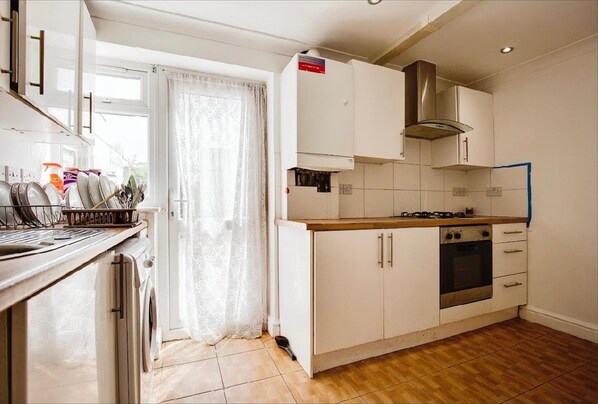A kitchen with white cabinets, a stainless steel range hood, a gas stove, and a built-in oven. - 3-bed - Sleeps 5 - Pets - Parking (Northolt)
