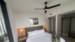 A hotel room with a bed, bedside tables, a ceiling fan, a framed picture on the wall, and a wardrobe. - 2-bedroom condo in amazing Miami with fitness room, AC, WiFi, heated pool (Miami)