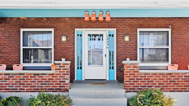 Un bâtiment en briques avec une porte blanche, portant le numéro 206, et un auvent bleu.