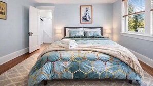 Une chambre à coucher avec un lit, une porte, une fenêtre et un tableau au mur.