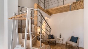 Un intérieur moderne avec un escalier en bois, un coin salon avec une petite table et une bouteille de vin.