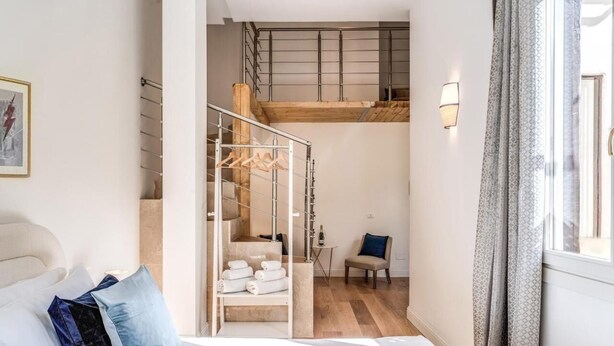 Une chambre à coucher comprenant un lit, une chaise, un escalier et un luminaire suspendu.