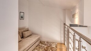 Un intérieur moderne avec un canapé beige, un tapis à motifs et un escalier doté de rampes en métal.