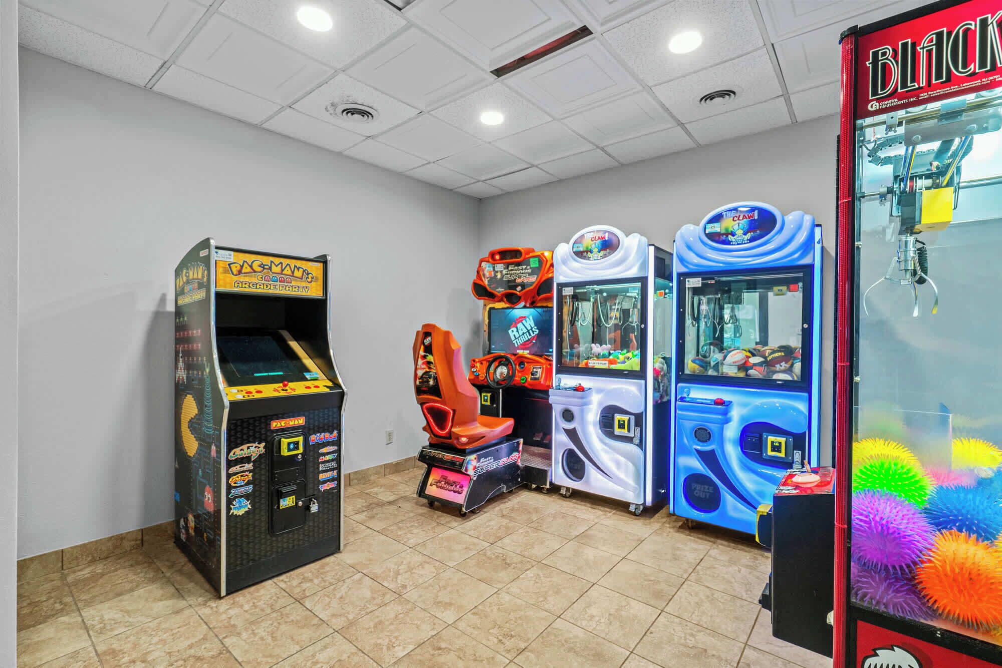 Una habitación con juegos de arcade, incluyendo Pac-Man, Super 3D Blitz y máquinas de garra.