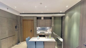 A modern kitchen with a built-in island, a dining area with chairs, and a wooden door. - ZHome-Suhe Luxury Mansion-Near the Bund (Shanghai)