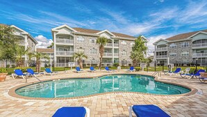 A swimming pool with lounge chairs and a stone building in the background. - Magnolia Pointe Unit 301 (Myrtle Beach)