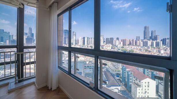 A high-rise room with large windows offering a cityscape view.