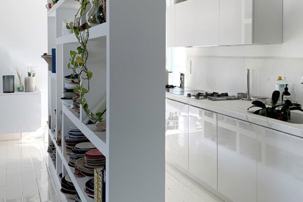 A modern kitchen with white cabinetry, a stainless steel countertop, and a variety of kitchenware on shelves. - Elegant beachfront villa with jacuzzi, garden, and panoramic terrace. (Montignano-Marzocca)