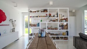 A modern kitchen with white cabinetry, a wooden dining table, and a variety of kitchenware and decorative items. - Elegant beachfront villa with jacuzzi, garden, and panoramic terrace. (Montignano-Marzocca)