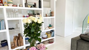 A modern living room with a white bookshelf filled with decorative items and a wooden coffee table with vases. - Elegant beachfront villa with jacuzzi, garden, and panoramic terrace. (Montignano-Marzocca)