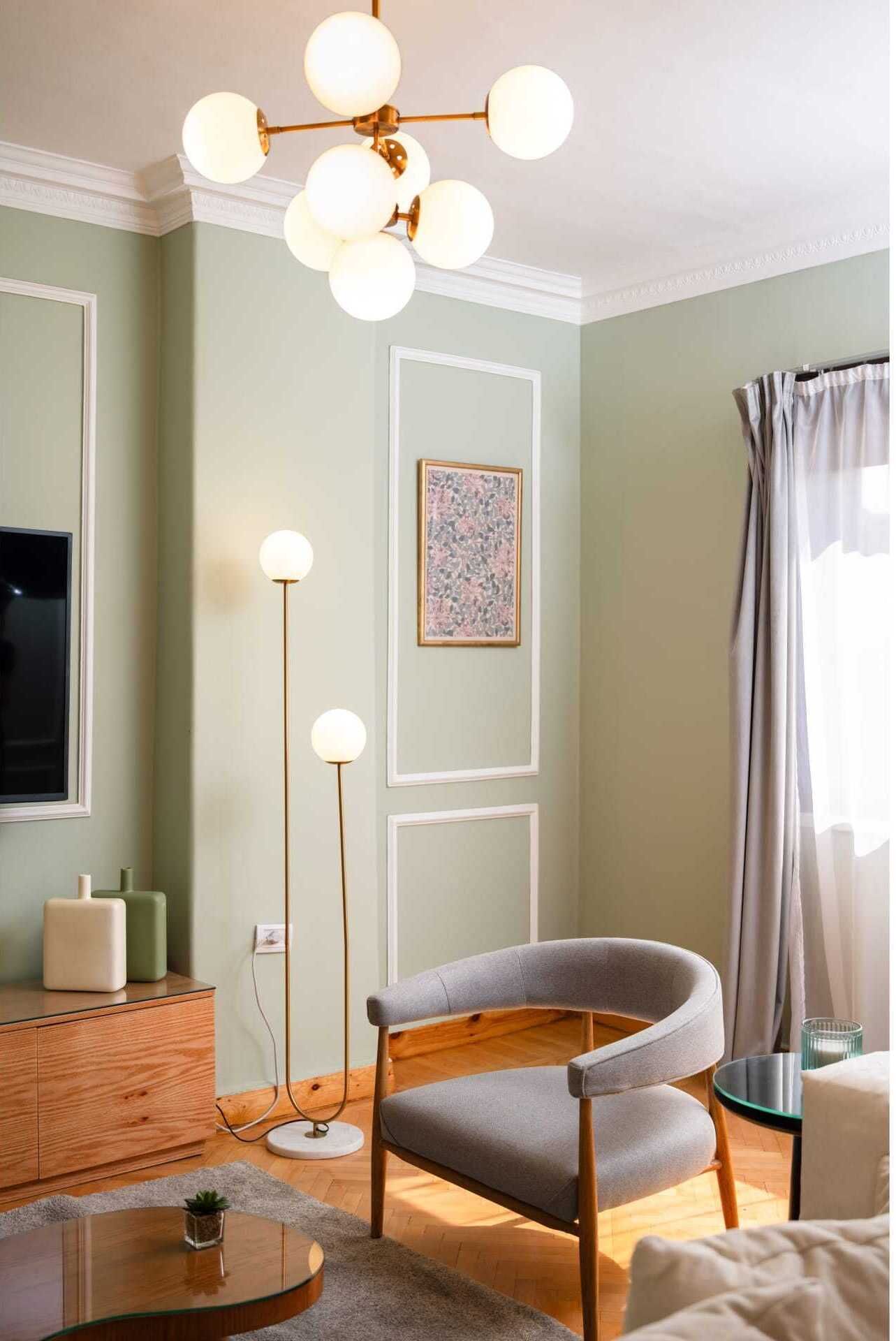 Una sala de estar con diseño moderno, que incluye un mueble de madera, un sillón tapizado en gris, una mesa de centro redonda de vidrio y una lámpara de pie.