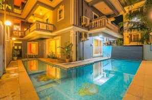 Ein mehrstöckiges Gebäude mit Pool, Balkonen und Außenbeleuchtung.