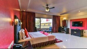 A modern hotel room with a bed, desk, chair, TV, and a balcony view. - The Royal Mirage (Candolim)