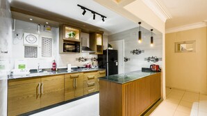 A modern kitchen with wooden cabinets, a central island, and a black refrigerator. - Xuru Stays I The Hospitable 2bdr Apt. 5 min From CAI Airport (Cairo)