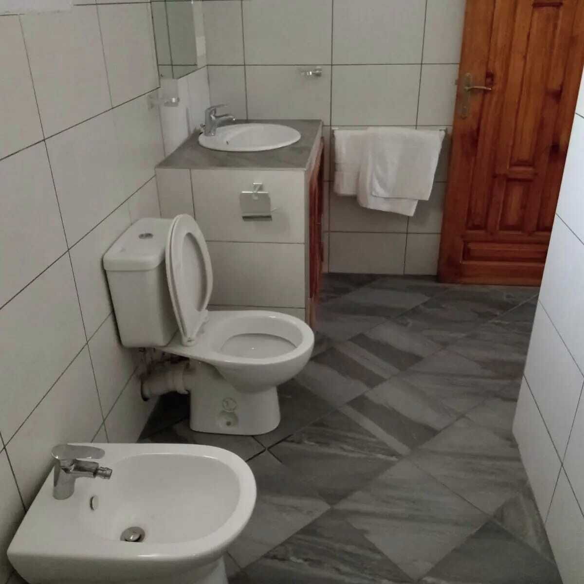 A small bathroom with a toilet, bidet, and sink.