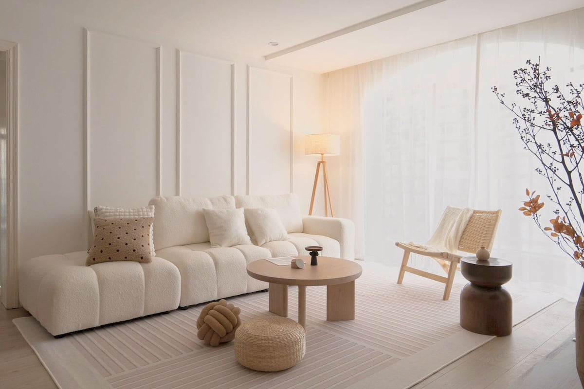 Een moderne woonkamer met een bank, een ronde salontafel, een bijzettafeltje, een vloerlamp en een fauteuil.