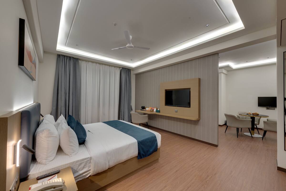 A modern hotel room with a bed, desk, and seating area.