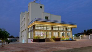 A modern building with a glass facade, a flat roof, and a well-lit entrance.