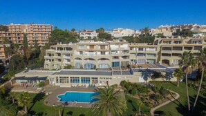 Un hôtel à plusieurs étages doté d’une piscine, entouré de verdure et d’autres bâtiments.