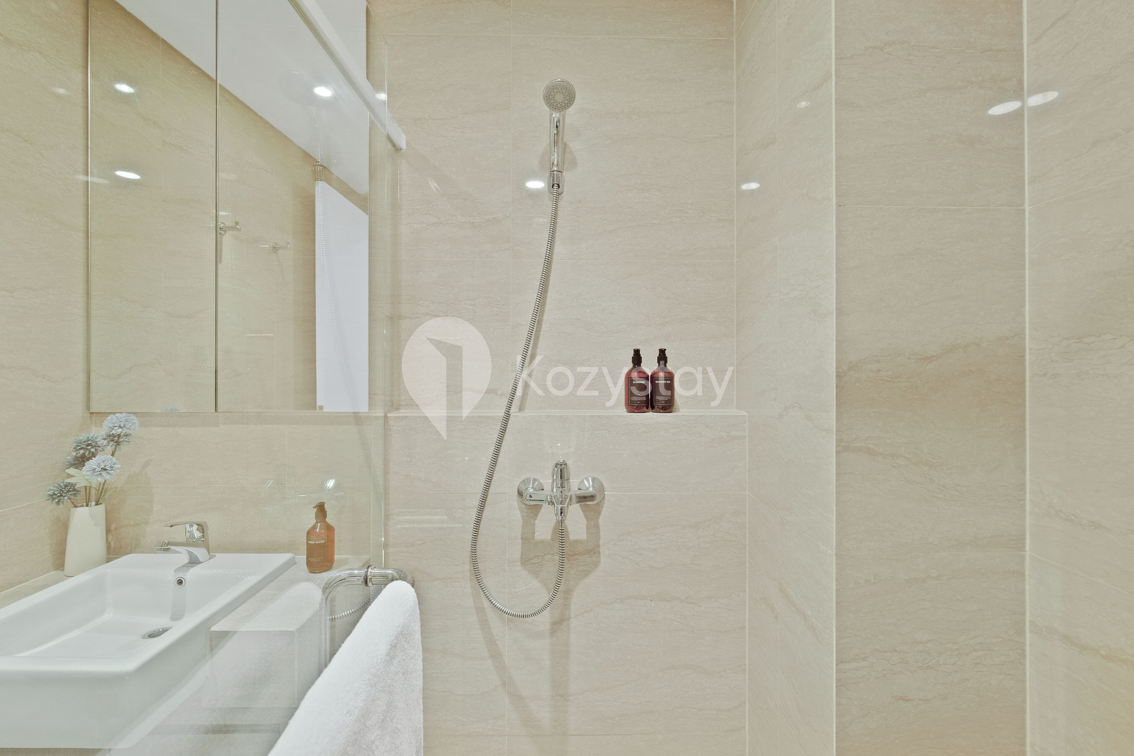 A modern bathroom with a glass-enclosed shower, a sink, and two bottles of shampoo on the wall.