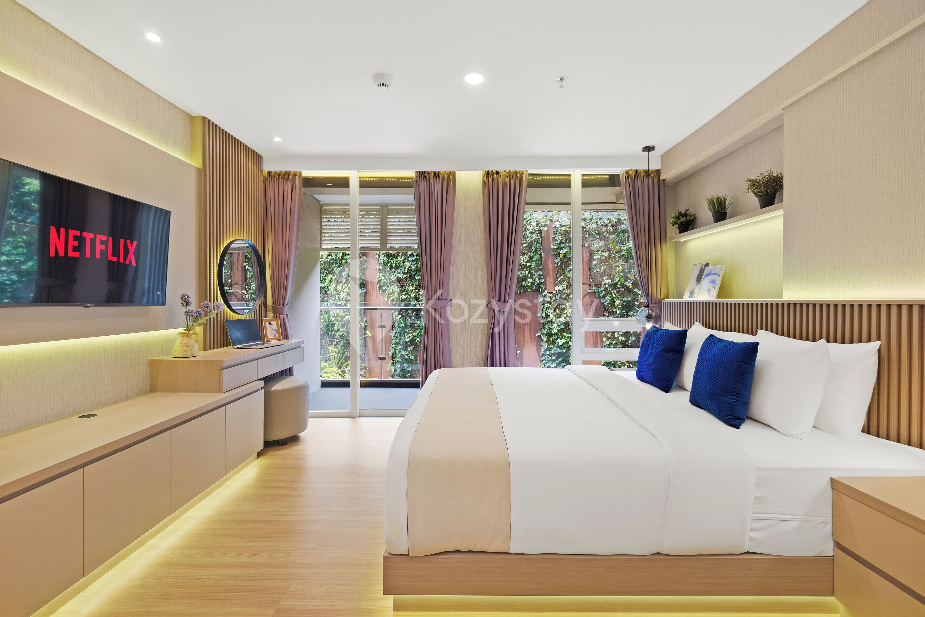 A modern bedroom with a large bed, a TV displaying 'NETFLIX', and a balcony with curtains.