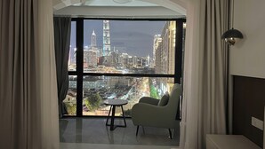 A hotel room with a large window offering a cityscape view, a bed, a chair, and a small table. - ZHome-Sun Garden-Amazing view (Shanghai)