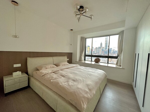 A bedroom with a bed, a nightstand, a window with a city view, and a ceiling fan. - ZHome-Sun Garden-Amazing view (Shanghai)