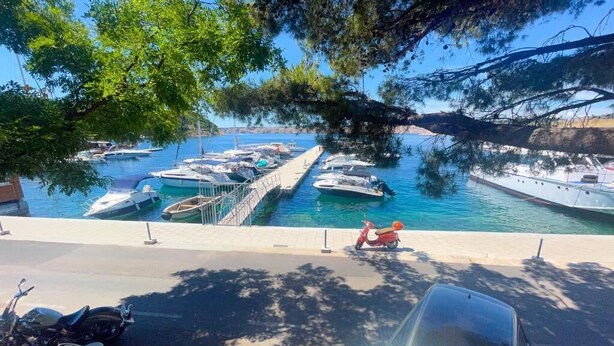 A marina with boats docked, a scooter, and a car parked on the side. - Apartment Dea 1 (Jadranovo)