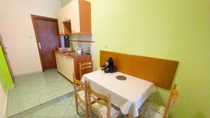 A compact kitchen with a dining table and chairs, a small refrigerator, and a microwave. - Apartment Dea 1 (Jadranovo)