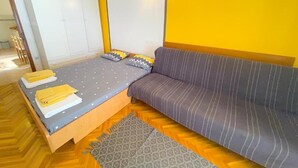 Et soveværelse med seng, sofa, garderobeskab og et mønstret tæppe.