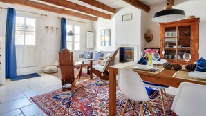 A dining area with a wooden table, white chairs, and a patterned rug. - House for 4 with garden - 500m from the beach (Barbâtre)