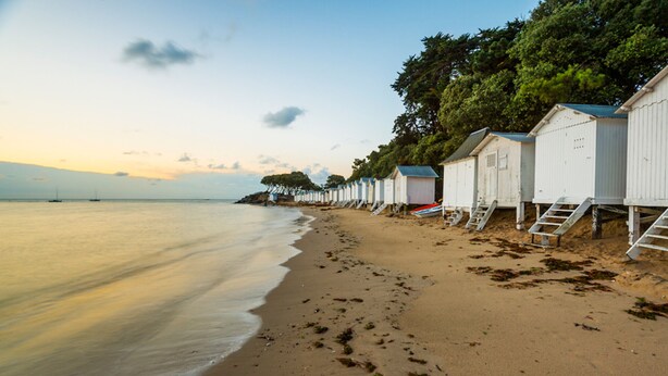 A beach with white beach huts and a calm sea. - House for 4 with garden - 500m from the beach (Barbâtre)
