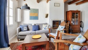 A living room with a sofa, chairs, a coffee table, a cabinet, and a fireplace. - House for 4 with garden - 500m from the beach (Barbâtre)