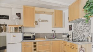 A compact kitchen with wooden cabinets, a white refrigerator, a toaster, and a sink.