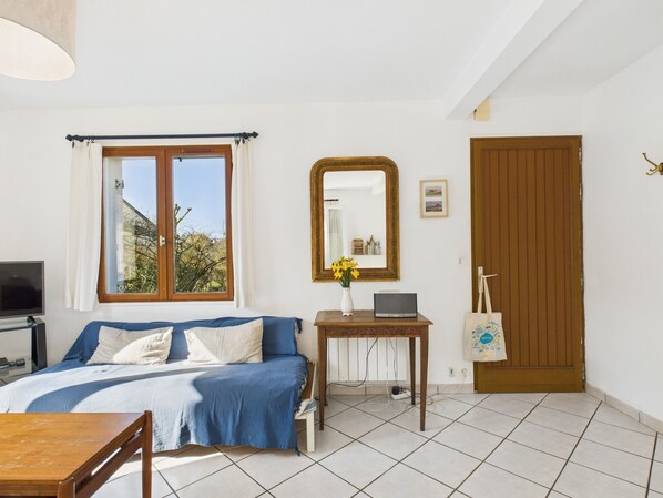 Un dormitorio con cama, escritorio, espejo y puerta.